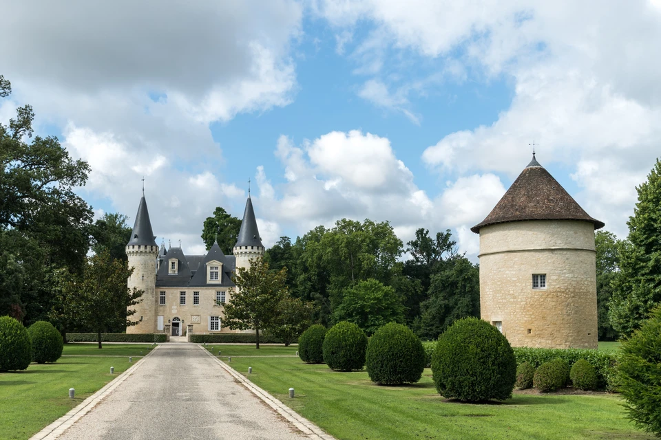 Château français avec tours médiévales à toitures coniques ardoisées, façade Renaissance en pierre calcaire, pigeonnier cylindrique