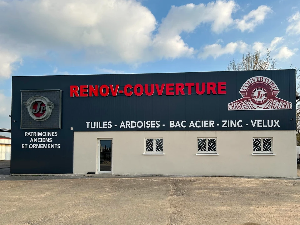 Couvreur professionnel travaillant sur toiture en tuiles métalliques, utilisant une échelle de toit pour accéder à une cheminée en briques